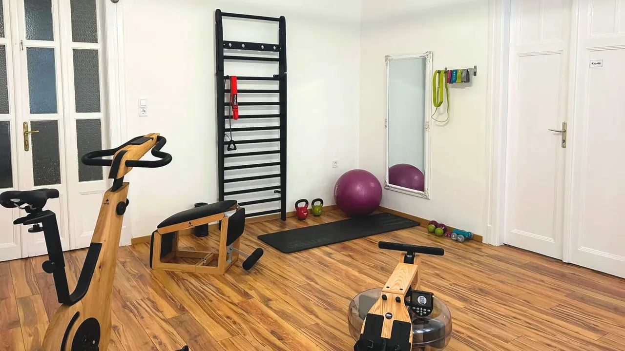 Világos mozgásterem szobakerékpárral, evezőgéppel, bordásfallal és fitneszlabdával